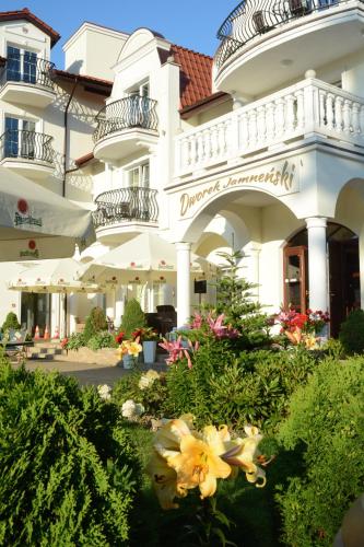 a large white building with flowers in front of it at Dworek Jamneński in Łazy