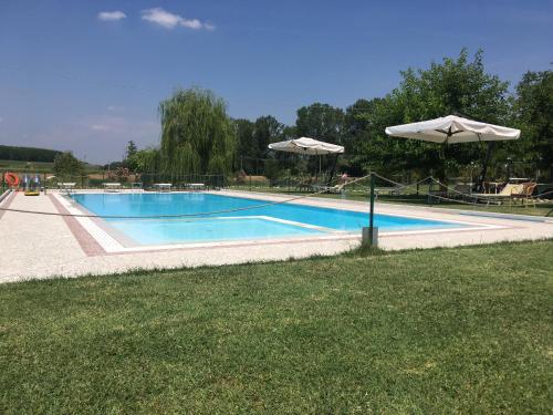 a large swimming pool with an umbrella and some grass at Agriturismo La Cascinetta in Pieve di Cento