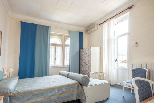 a bedroom with blue curtains and a bed and a window at Hotel Maderno in Toscolano Maderno