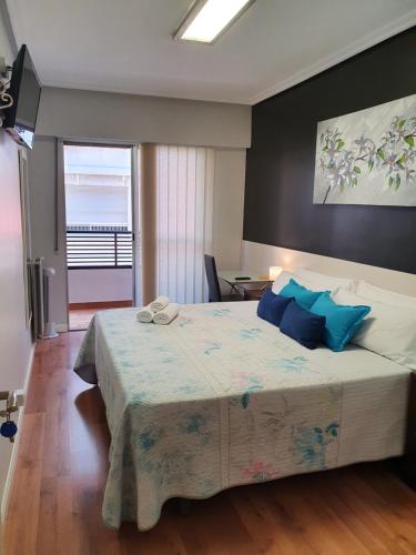 a bedroom with a large bed with blue pillows at Pensión El Espolón in Logroño