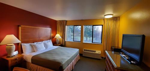 a hotel room with a bed and a flat screen tv at Olympic View Inn in Sequim