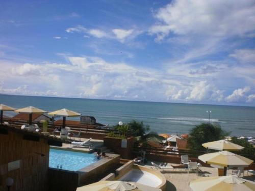a view of a swimming pool with umbrellas and the ocean at Pipa´s Ocean Flat in Pipa