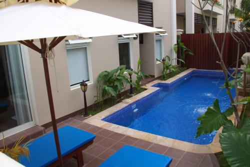 a pool with an umbrella next to a house at Bali Hotel in Phnom Penh
