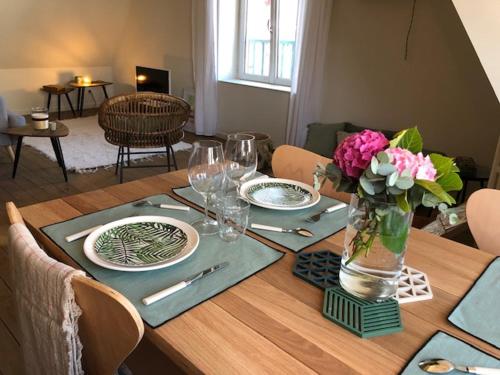 une table en bois avec des assiettes et des fleurs dans un vase dans l'établissement L'OASIS, à Le Touquet-Paris-Plage