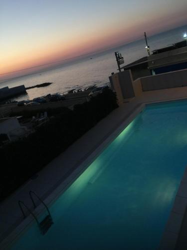 a swimming pool in front of the ocean at sunset at Palese Profumo di Mare in Santo Spirito