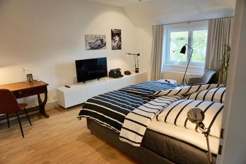 een slaapkamer met een bed, een bureau en een televisie bij Privatzimmer Schönfelder in Düsseldorf