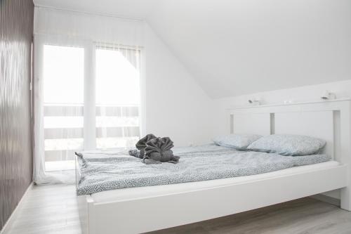 a white bedroom with a large bed with a window at Kardos Villa in Szigliget