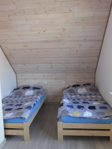 Dos camas en una habitación con paredes de madera. en Morskie Zacisze, en Łeba