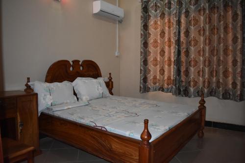 a bedroom with a wooden bed and a window at Lunguya Lodge in Dar es Salaam