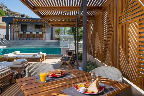 un patio con una mesa con comida y una piscina en Casa D'Irene Deluxe Hotel, en Falasarna