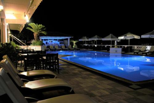 a swimming pool at night with chairs and umbrellas at King Minos Hotel in Tolo