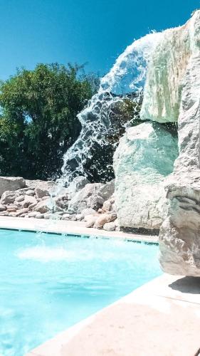 a swimming pool with blue water and rocks at Bellavista Relax Hotel in Levico Terme