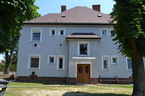 a white house with a brown door at Fészek Apartmanház in Tapolca