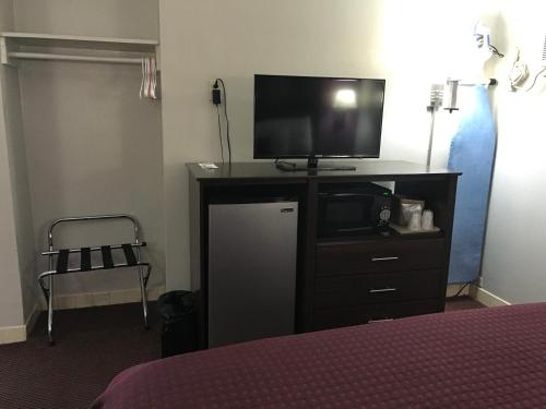 a bedroom with a tv on a dresser with a bed at Silver Princess Motel in Ocala