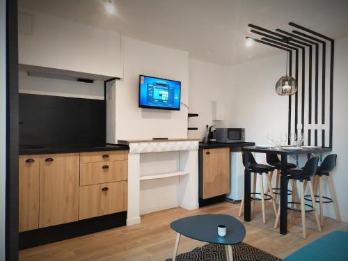 a kitchen with a table and a tv on the wall at PARADISE sur Mer, Terrasse, Spa,Proximité Nausicaa, Plage, Restaurants in Boulogne-sur-Mer