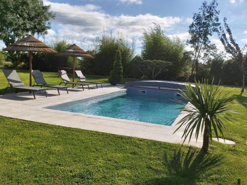 une piscine avec chaises et parasols dans une cour dans l'établissement Les Marguerites, à Champdolent
