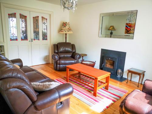 a living room with leather furniture and a coffee table at Holiday Cottages Portsalon in Portsalon