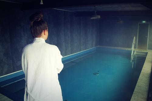 a woman is standing in a room with a pool at 360 Hotel & Thermal Baths in Selfoss