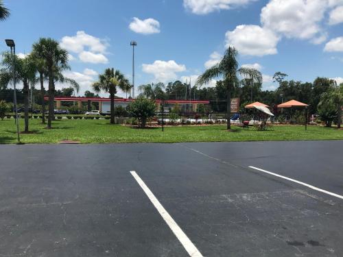 an empty parking lot with a building and palm trees at Silver Princess Motel in Ocala