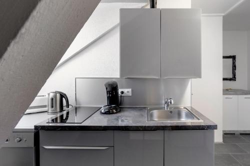 a kitchen with white cabinets and a sink at Comfort Stay Basel Airport 3B46 in Saint-Louis