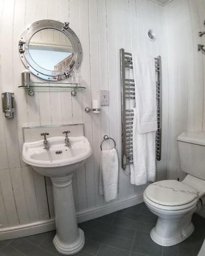 a bathroom with a sink and a toilet and a mirror at Bridge House Bed & Breakfast in Boscastle
