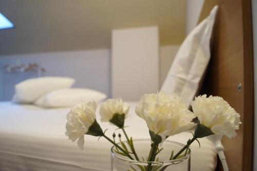 a vase with white flowers on a table next to a bed at Bonjour Bonheur in Avellino