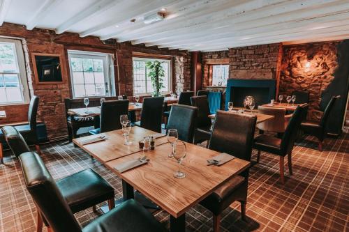um restaurante com mesas e cadeiras de madeira e paredes de tijolo em Royal Oak Appleby em Appleby
