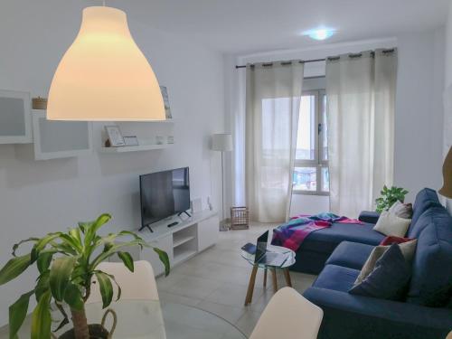 a living room with a blue couch and a tv at Citybeach - parking & wifi in Las Palmas de Gran Canaria