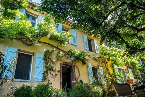 a yellow building with blue windows and trees at domaine des tilleuls d'or in Saint-Cézaire-sur-Siagne