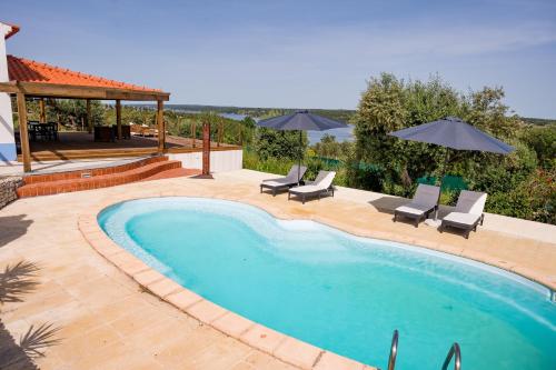 a swimming pool with chairs and umbrellas in a yard at Monte da Cegonha Preta in Montargil