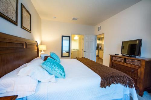 a bedroom with a bed with blue pillows and a television at HAPPY PORT, a sua casa na Disney in Kissimmee