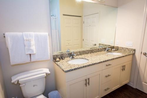 a bathroom with two sinks and a toilet and a mirror at HAPPY PORT, a sua casa na Disney in Kissimmee