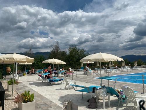 a pool with chairs and tables and umbrellas at Il Pozzo Country House in Collescipoli
