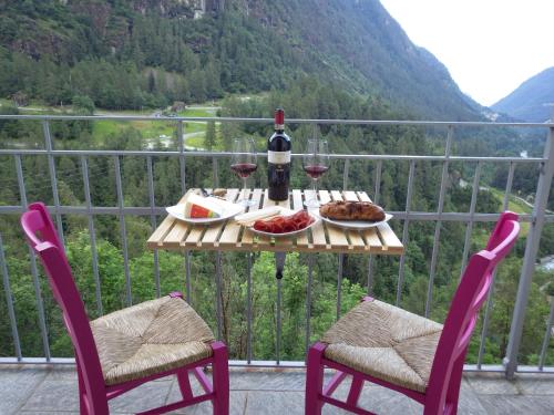 a table with wine glasses and food on a balcony at AltaValle Holiday Home, monolocale Pink e bilocale Lime in Chiesa in Valmalenco