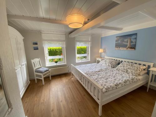 a bedroom with a white bed and two windows at Ferienwohnung Alte Schmiede in Wangerland