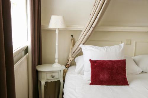 a bed with a red pillow next to a window at Auberge de Campveerse Toren in Veere