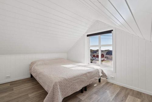 a white bedroom with a bed and a window at Ragnahuset - Koselig minihus i fiskevær in Skaftneset