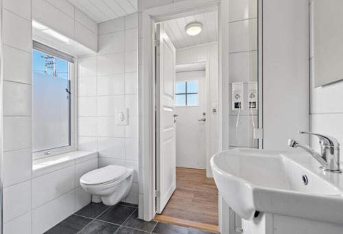 biała łazienka z toaletą i umywalką w obiekcie Ragnahuset - Koselig minihus i fiskevær w mieście Skaftneset