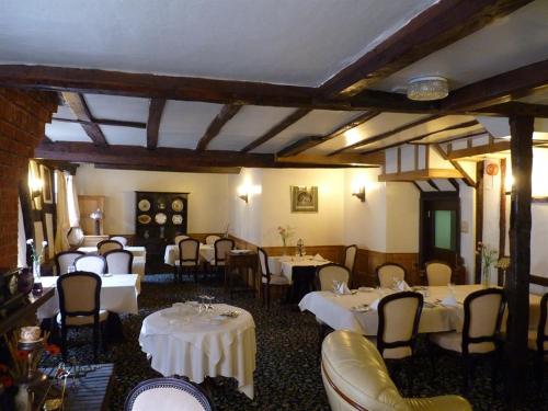 uma sala de jantar com mesas e cadeiras brancas em The Falcon Hotel em Bromyard