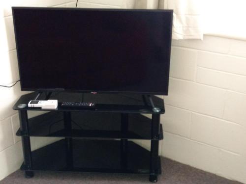 a tv on a black stand with a keyboard and a monitor at Millicent Motel in Millicent