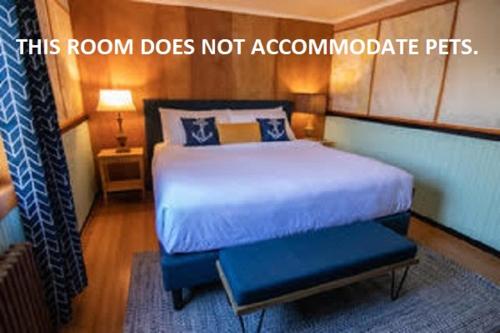 a bedroom with a bed with a blue foot stool at Anchor Inn Resort in Lincoln City