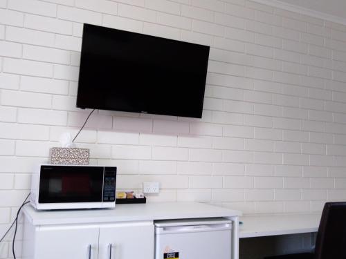 a tv hanging on a wall with a microwave at Millicent Motel in Millicent