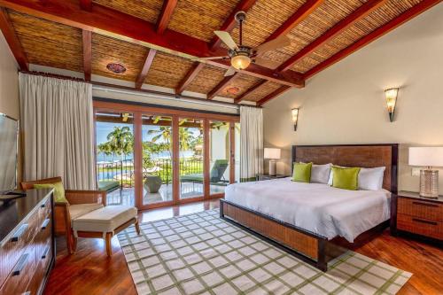 a bedroom with a large bed and a balcony at Spacious Open-Concept Condo with Stylish Design, Direct Beach Access & Resort-Style Amenities in Playa Flamingo