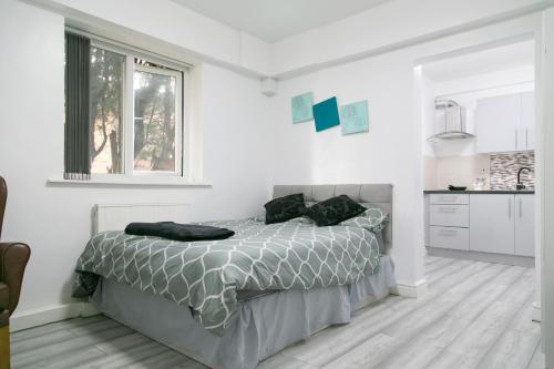 een witte slaapkamer met een bed en een raam bij Cheetham Hills Apartments in Manchester