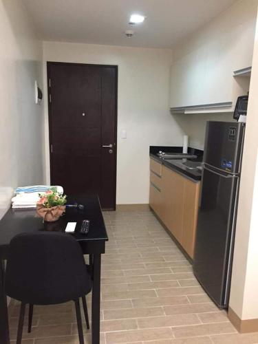 a kitchen with a table and a black refrigerator at Furnished Studio Megaworld 7M in Iloilo City