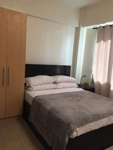 a bedroom with a large bed with white pillows at Furnished Studio Megaworld 7M in Iloilo City