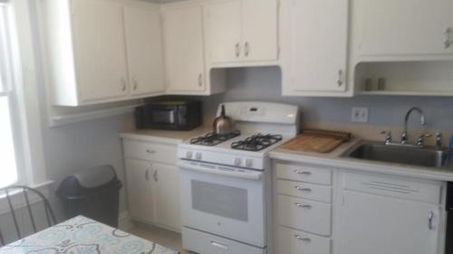 a kitchen with white cabinets and a stove and a sink at E Michigan Walk Up Furnished 1 Bedroom APT in Lansing