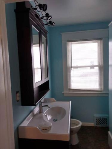a bathroom with a sink and a mirror and a toilet at E Michigan Walk Up Furnished 1 Bedroom APT in Lansing