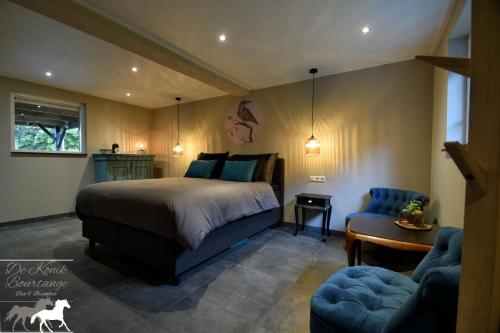 a bedroom with a bed and a chair and a table at B&B De Konik Bourtange in Bourtange