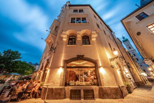a tall building with people sitting outside of it at Hotel Am Markt in Munich